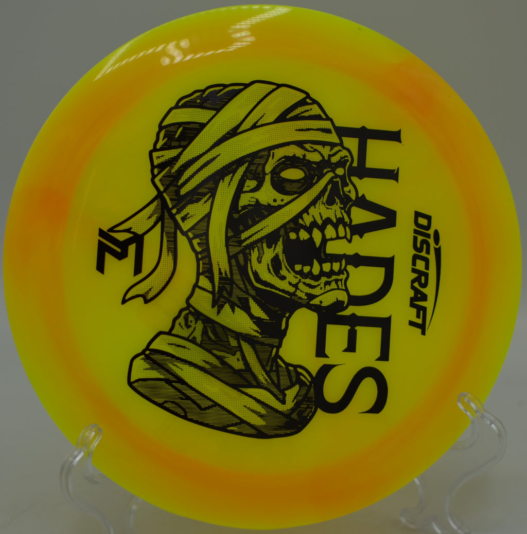 Z Swirl Mummified Hades slicing through a wooded fairway on a long, controlled drive at The Fort Disc Golf Course in Ogden, Utah.