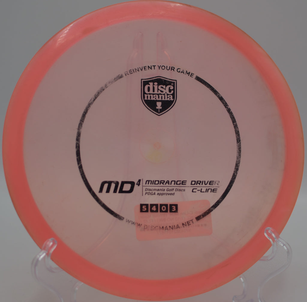 Used C-Line MD4 (Innova Made) resting beside the basket after a straight midrange shot at Blue Ribbon Pines Disc Golf Course in East Bethel, Minnesota.