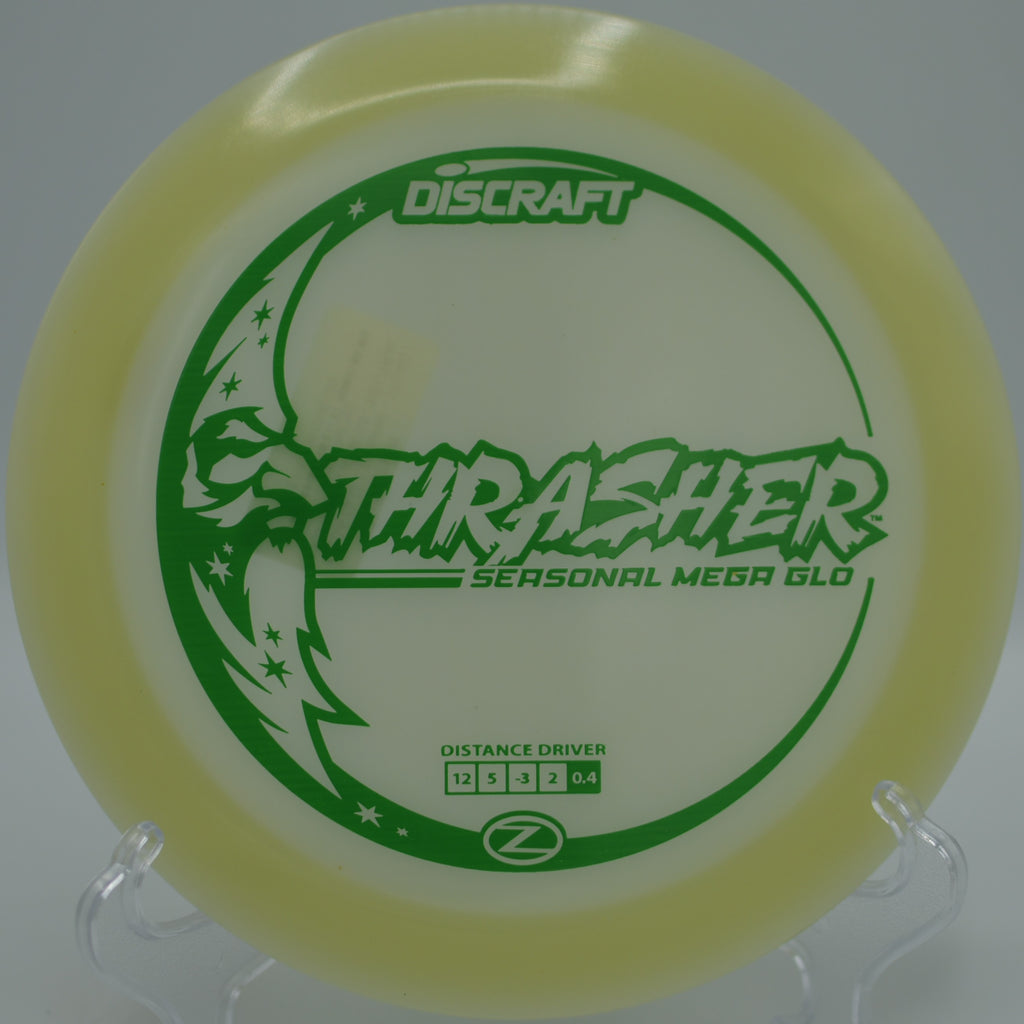 Mega Glow Z Thrasher glowing mid-flight on a smooth hyzer-flip at Maple Hill Disc Golf Course in Leicester, Massachusetts.