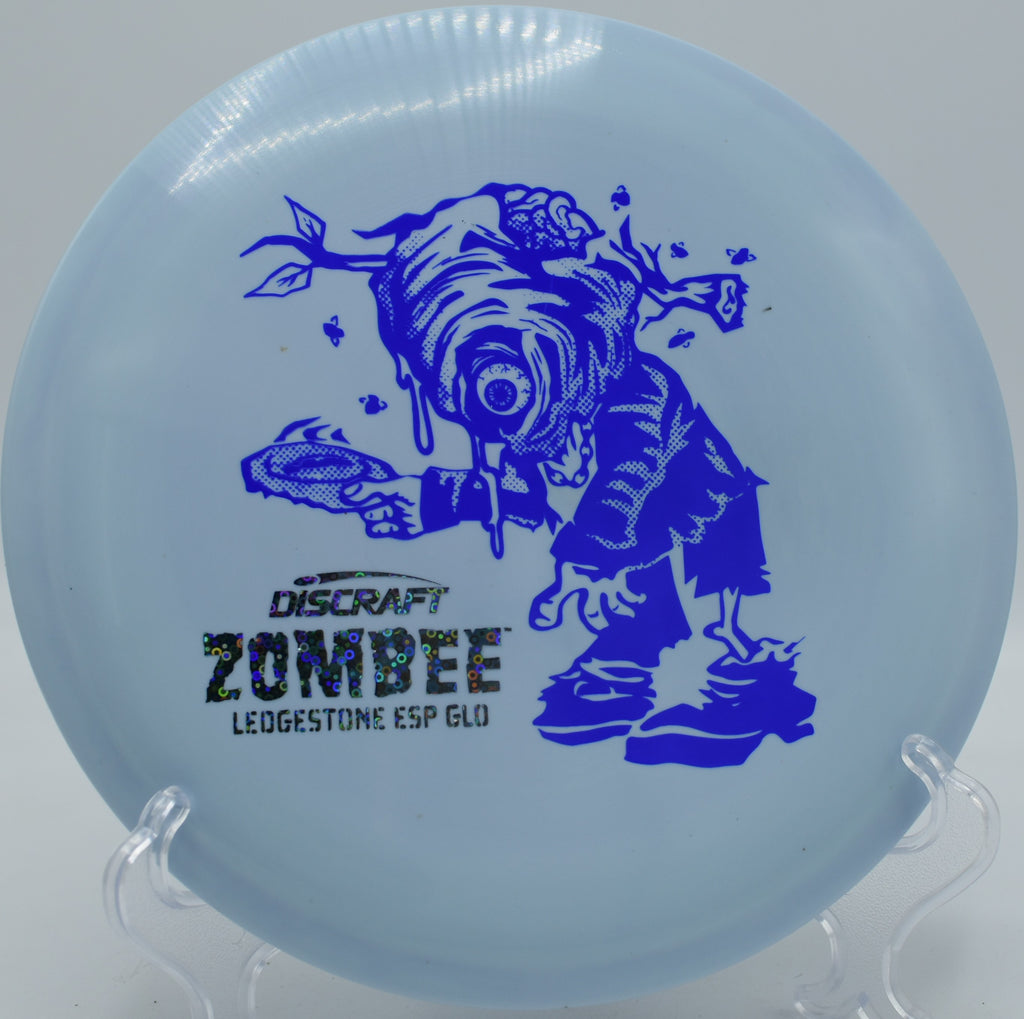 Glowing ESP Zombee flying straight down a wooded fairway at Idlewild Disc Golf Course in Burlington, KY.