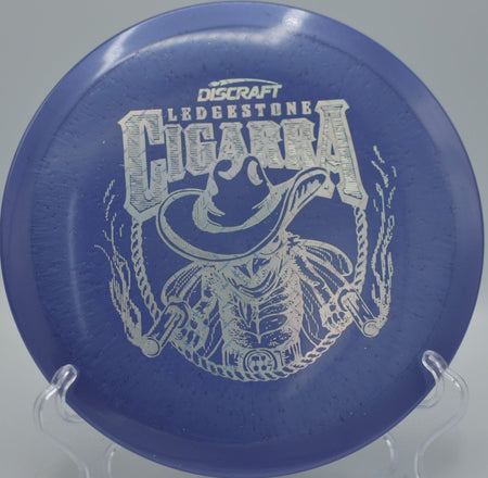 Discraft Ti Sparkle Cigarra from the 2026 Ledgestone Series flying a smooth hyzer flip through tight fairways at Harmony Bends Disc Golf Course in Columbia, Missouri