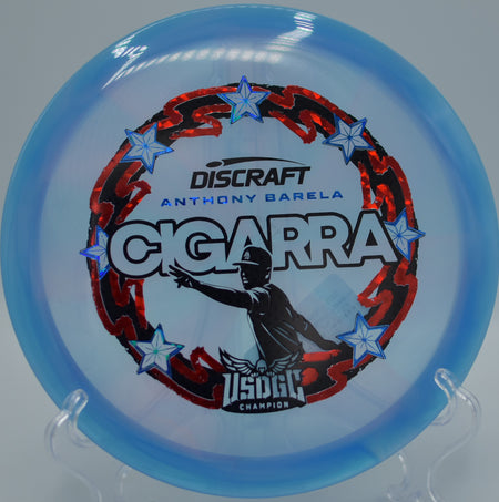 Swirled Z-Swirl Cigarra set on the wooded fairway at The Ruins DGC in Newark, DE, built for controlled turnovers and straight lines.