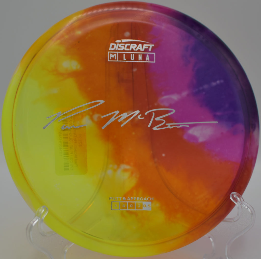 Fly Dye McBeth Z Luna laying on the tee pad at Idlewild DGC in Burlington, KY, ideal for controlled putting and accurate approach shots.