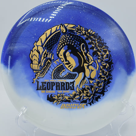 Duo Leopard3 Ohn Scoggins Tour Series fairway driver resting beside basket chains after a soft approach at Andrew Jackson State Park Disc Golf Course in Lancaster, South Carolina