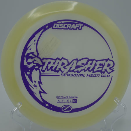 Mega Glow Z Thrasher glowing green as it glides past pines at Idlewild Disc Golf Course in Burlington, Kentucky.