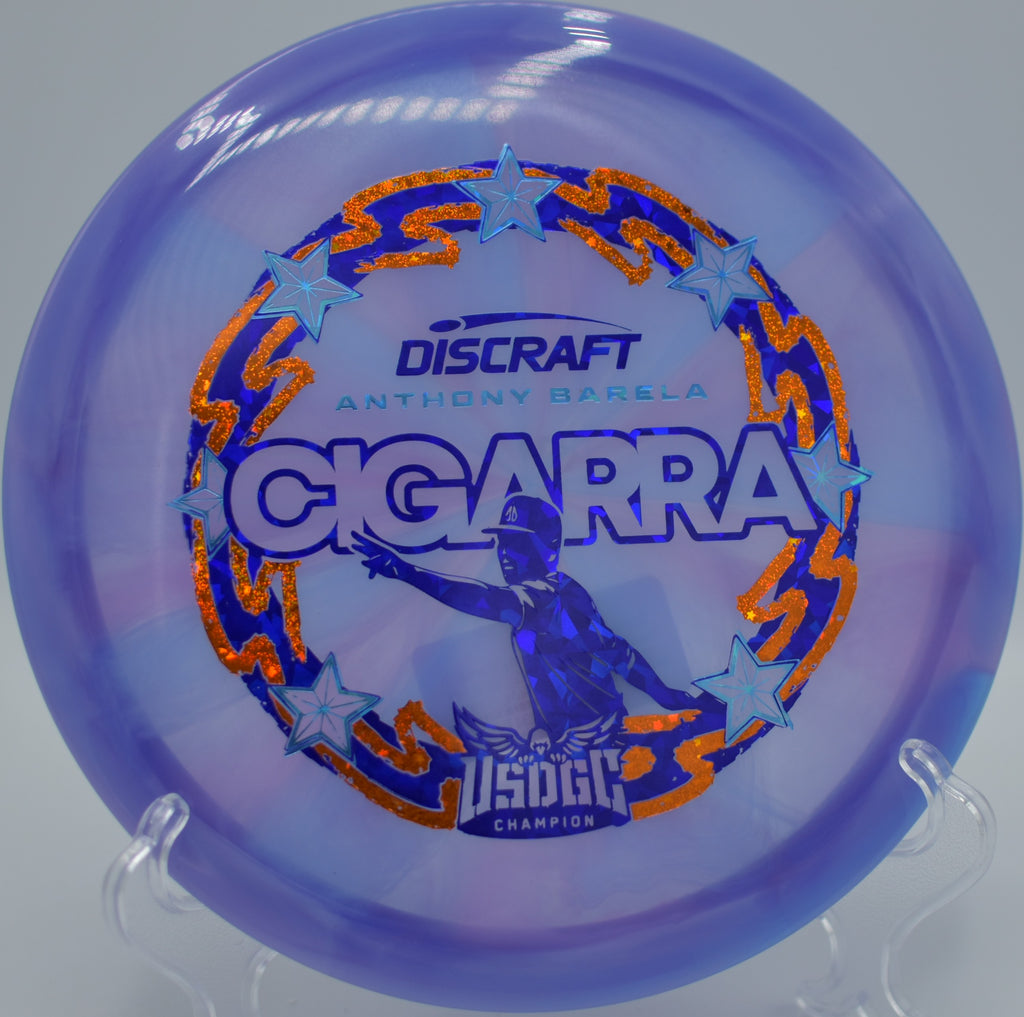 Swirled Discraft Cigarra resting near the basket at Wills Park DGC in Alpharetta, GA, perfect for smooth straight-to-fade flights.