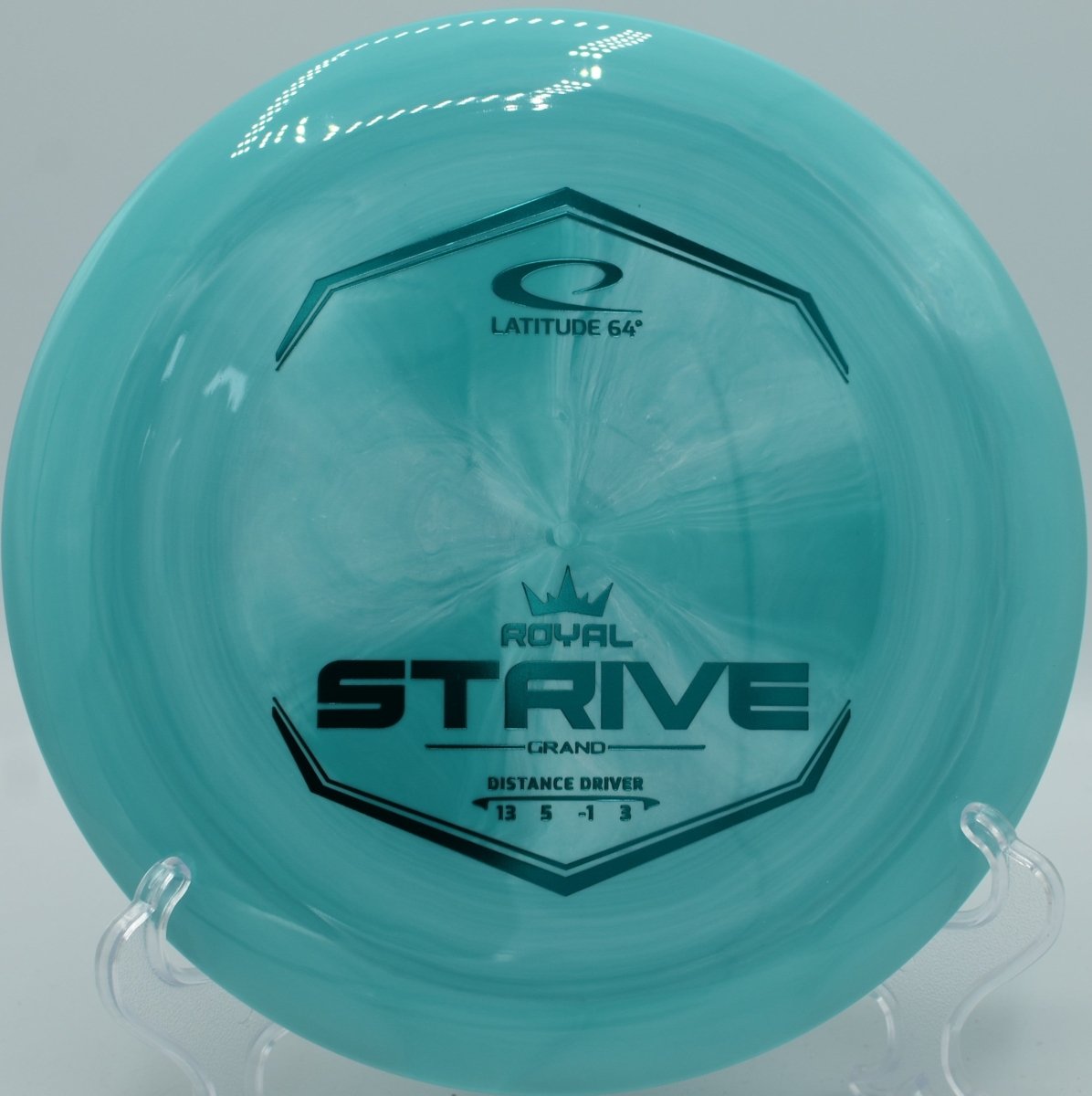 Grand plastic Strive distance driver resting near basket chains at Blue Ribbon Pines Disc Golf Course in East Bethel, Minnesota
