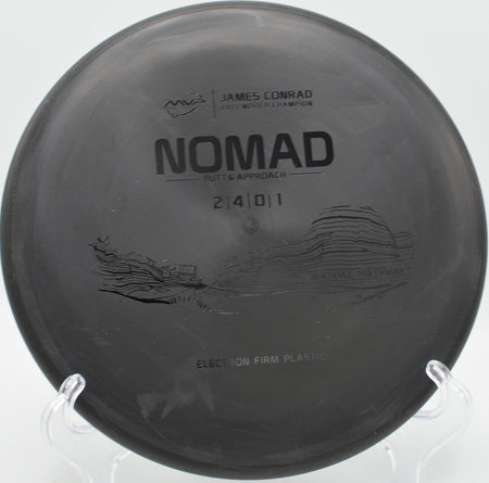 Electron Firm Nomad putter resting near chains after a glidey approach at Bryan Park Disc Golf Course in Greensboro, North Carolina