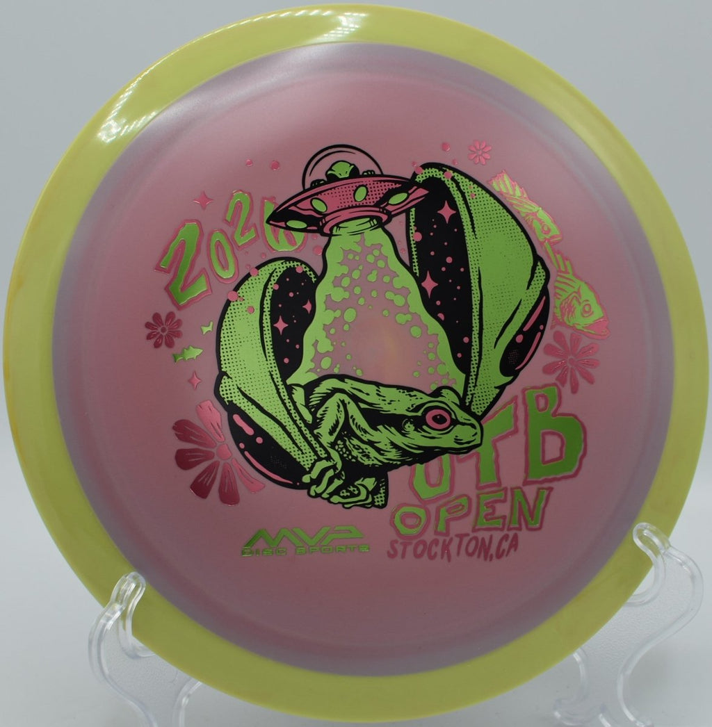 2026 OTB Open Fission Delirium driver lying next to basket pole at Trophy Club Disc Golf Course in Trophy Club, Texas