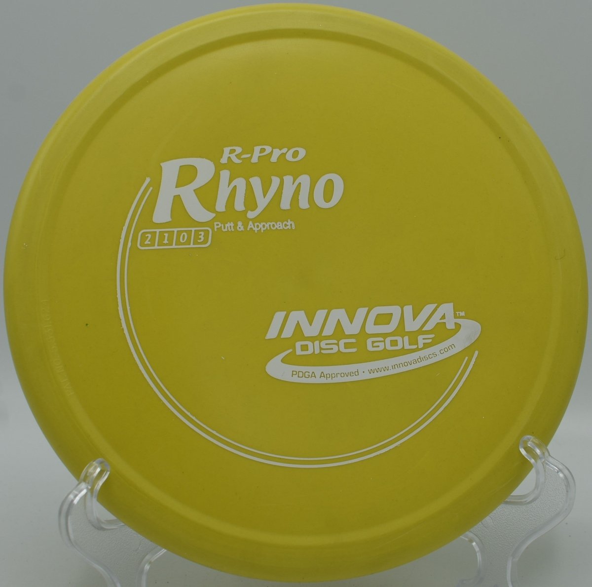 R-Pro Rhyno overstable putter resting on the putting green beside the cage at Sunrise Park Disc Golf Course in Las Cruces, New Mexico