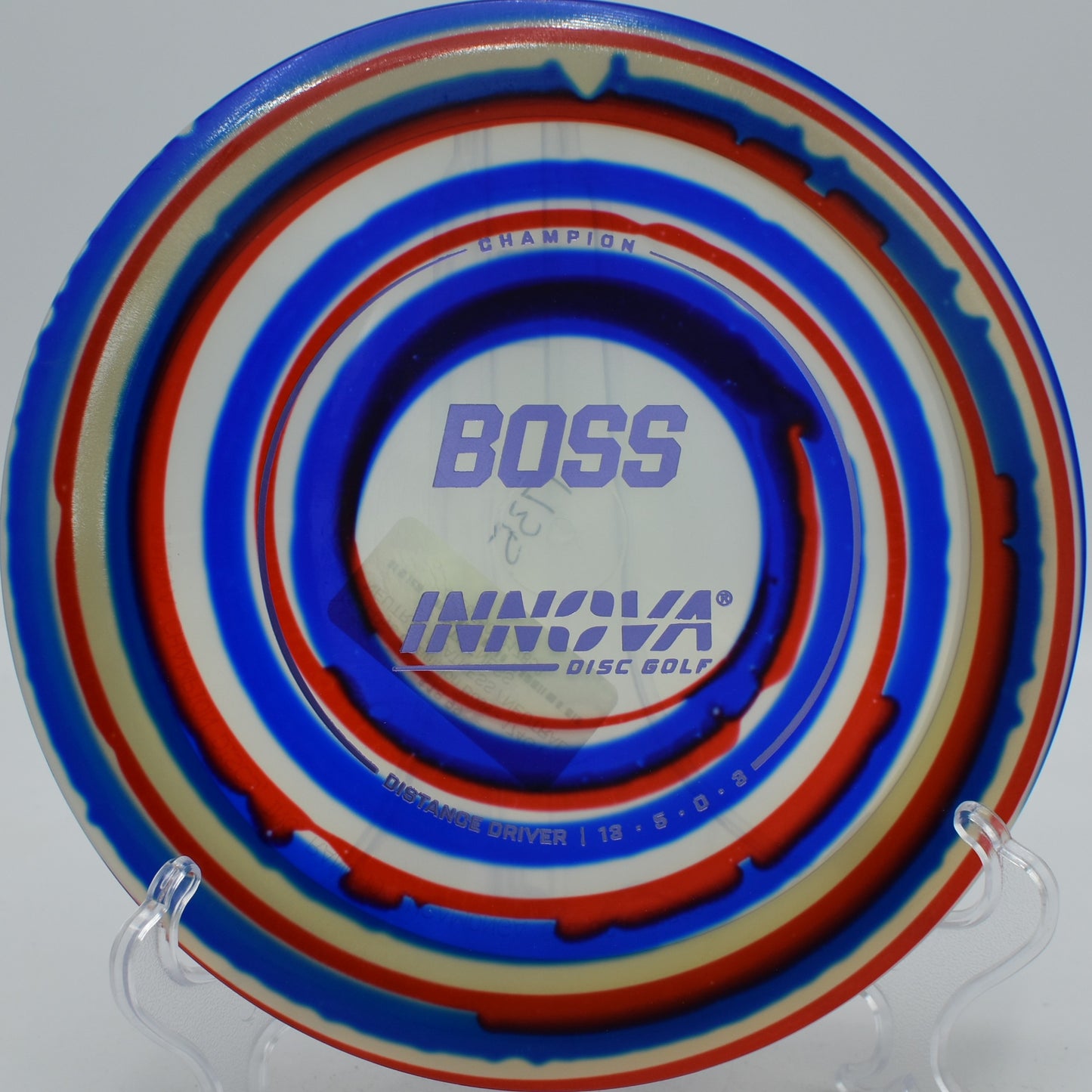Colorful I-Dye Boss disc launched forehand off the tee pad at Harmony Bends Disc Golf Course in Columbia, Missouri