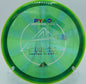 Close-up of the Prism Proton Pyro disc placed on a dirt path at DeLaVeaga Disc Golf Course, reflecting its premium plastic and reliable flight characteristics.