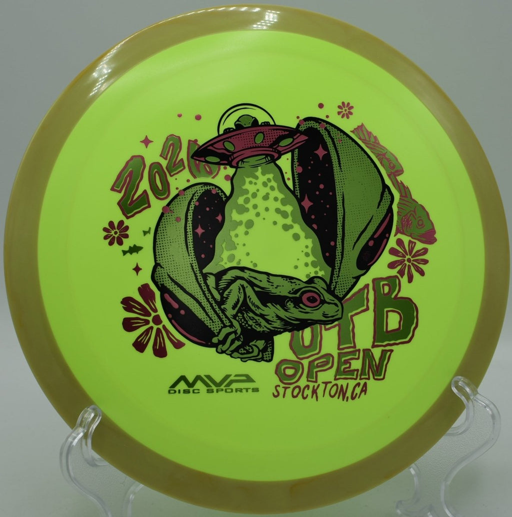 OTB Open 2026 Delirium Fission plastic distance driver resting in pine needles at Sandy Point Disc Golf Ranch in Lac du Flambeau, Wisconsin