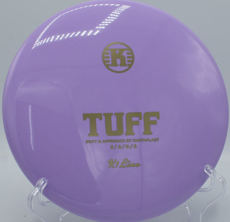 K1 Tuff putt and approach disc resting near chains after a glidey upshot at Centennial Park Disc Golf Course in Lawrence, Kansas