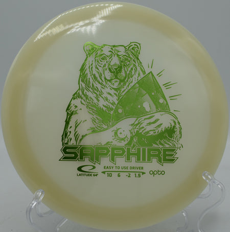 Latitude 64° Opto Moonshine Sapphire glowing lightweight driver soaring on a hyzer-flip at Maple Hill Disc Golf Course in Leicester, Massachusetts.
