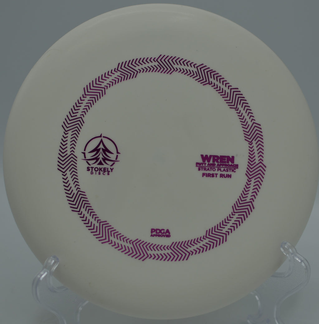 Player throwing a Strato Wren on a straight approach through tight trees at Toboggan Disc Golf Course in Milford, Michigan.