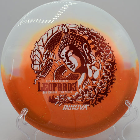 Duo Leopard3 Ohn Scoggins Tour Series fairway driver lying beside the basket pole at Dry Creek Parkway Disc Golf Course in Modesto, California