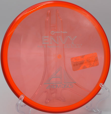 Proton Envy disc on a green tee pad, ready for a putt at Zobel Memorial Disc Golf Course in Fairview, Pennsylvania, with a smooth and predictable finish.