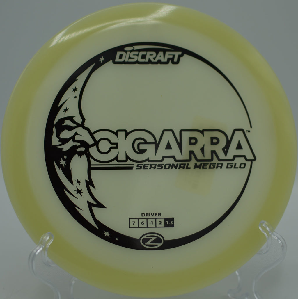 Mega Glow Z Cigarra glowing mid-flight over fairway trees at Idlewild Disc Golf Course in Burlington, Kentucky.