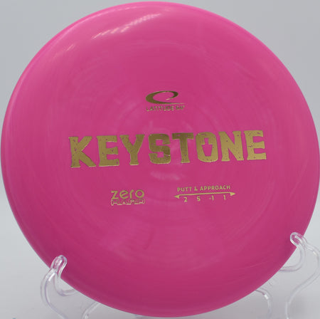 Latitude 64° Zero Hard Keystone lying on trimmed grass at Sabattus Disc Golf Course in Sabattus, Maine, designed for consistent putting in all conditions.

