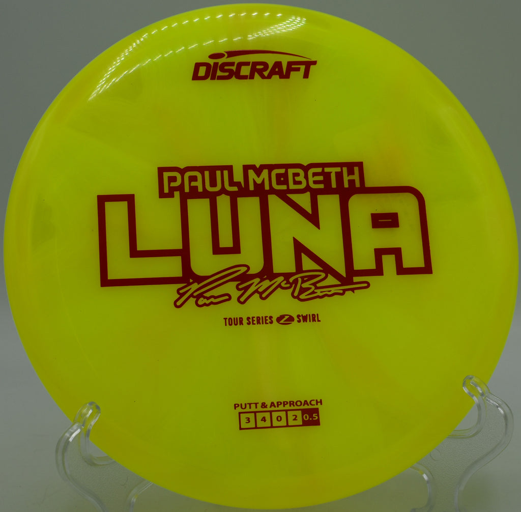 Discraft Z Swirl Luna glowing under overcast skies at Sabattus Disc Golf Course in Maine, offering dependable stability for short drives.


