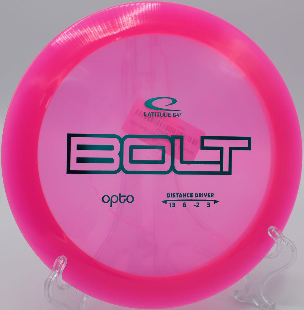 Opto Bolt golf disc spinning mid-flight over a serene lake at Tall Pines Disc Golf Park.