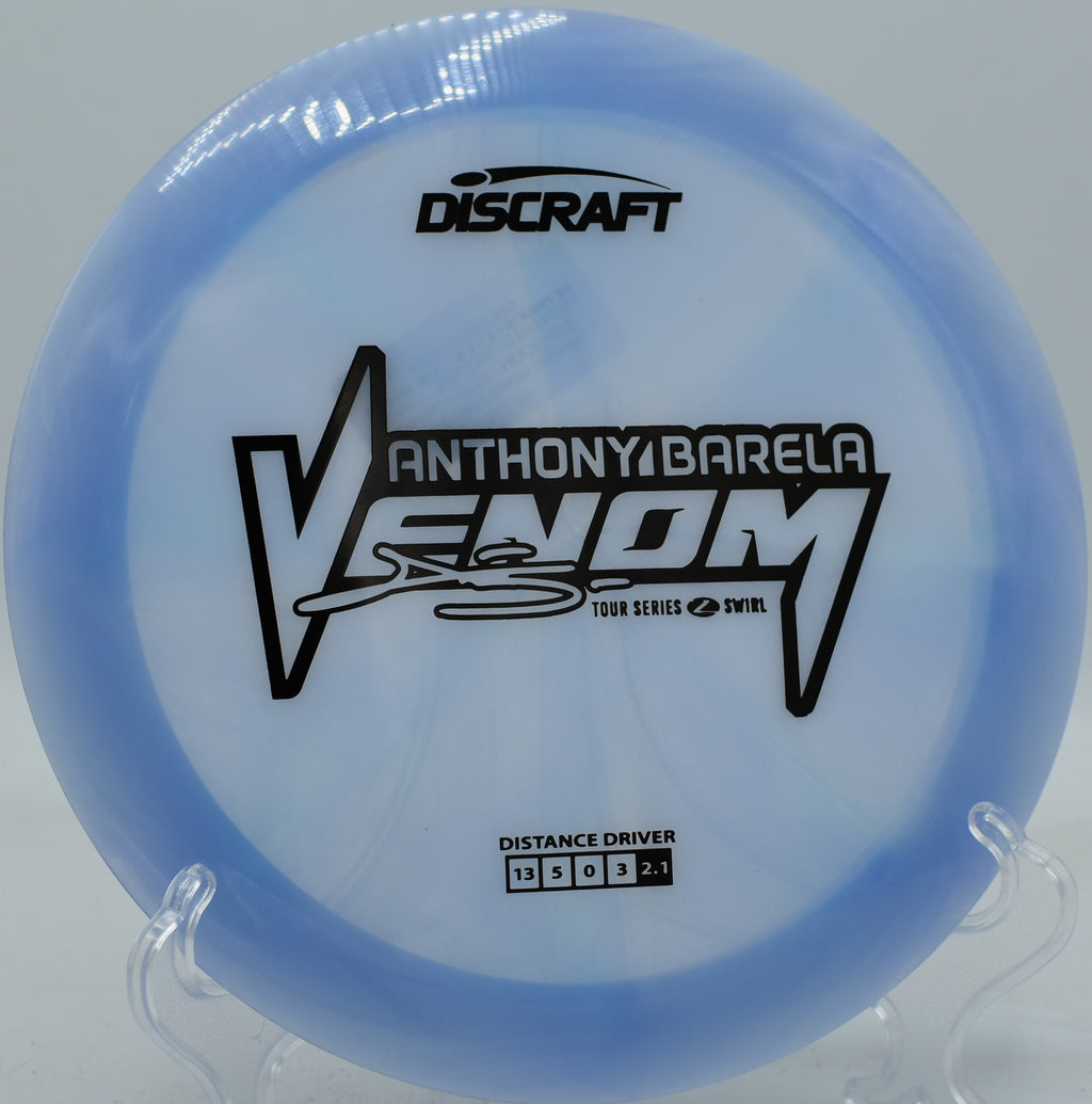 Z Swirl Venom tearing through a crosswind with a sharp hyzer angle, fading predictably toward the pin at Idlewild Disc Golf Course.

