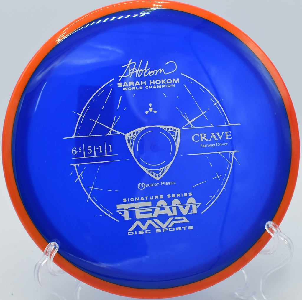 The Neutron Crave resting on a wooden table, with sunlight highlighting its premium Neutron plastic and smooth edges, taken on the tee pad at Beaver Farms Disc Golf Course in Lincoln, Nebraska.

