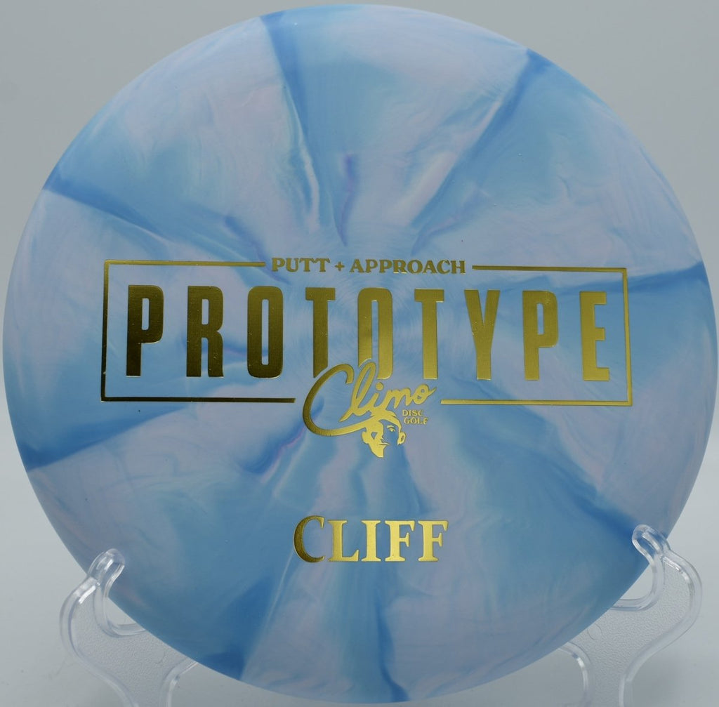 Climo Cliff beadless putter mid-putt toward chains at Idlewild Disc Golf Course in Burlington, Kentucky tight wooded hole