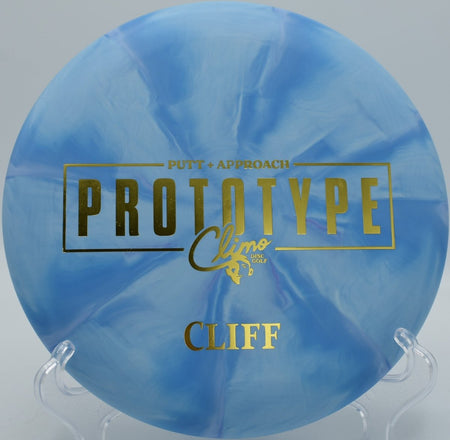 Trophy Line Cliff putter resting near basket at Blue Ribbon Pines Disc Golf Course in East Bethel, Minnesota during league play