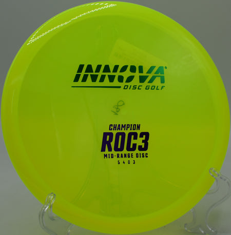 An Innova Champion Roc3 holding a slight anhyzer line at BlueGill Disc Golf Course in Wayland, Michigan, threading the wooded gap.