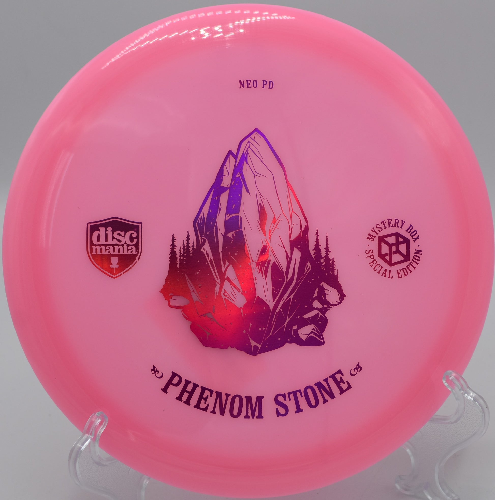 "Neo Essence The Phenom Stone disc golf driver with a sleek design, photographed mid-flight at Maple Hill Disc Golf Course in Leicester, MA."
