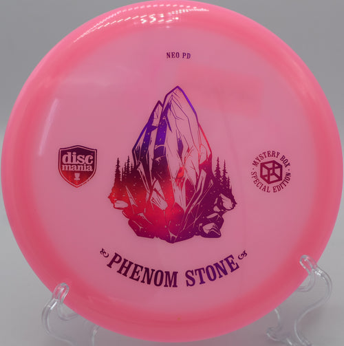 "Neo Essence The Phenom Stone disc golf disc resting near a basket at Blue Ribbon Pines Disc Golf Course in East Bethel, MN, showcasing its lightweight control."
