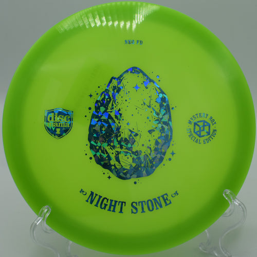 "Night Stone Neo Essence disc resting near a basket at Flyboy Aviation Disc Golf Course in Whitesburg, GA, highlighting its premium Neo plastic."
