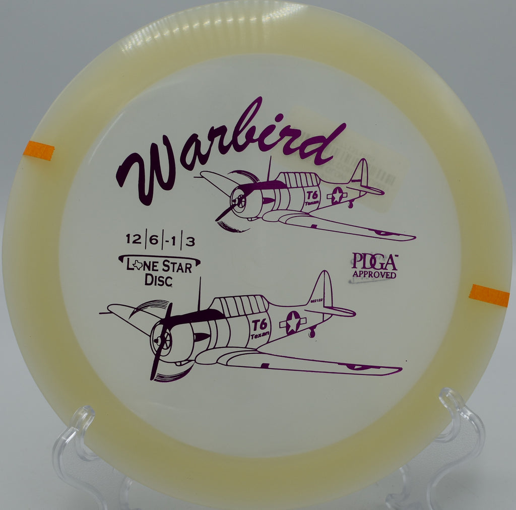 "Glow Warbird disc resting near the basket after a clean approach in Charlotte, North Carolina, perfect for finishing strong."
