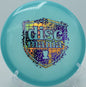 Discmania Neo Lumen Origin resting on a tee pad under low light at O'Hauser Park in Menasha, Wisconsin

