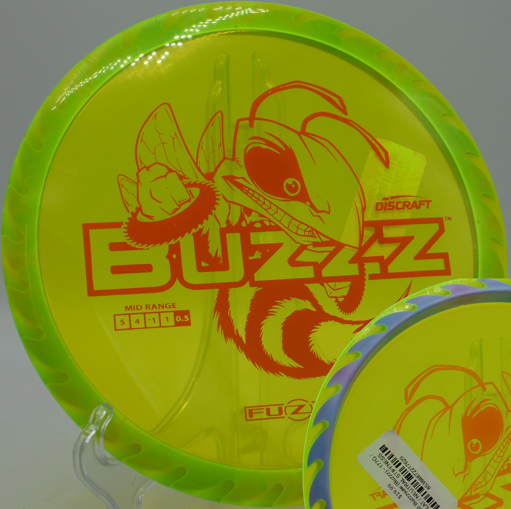 Fuzed plastic Buzzzsaw resting on sunlit grass at Lake Marshall Disc Golf Course in Montross, Virginia, built for torque-heavy midrange flights.


