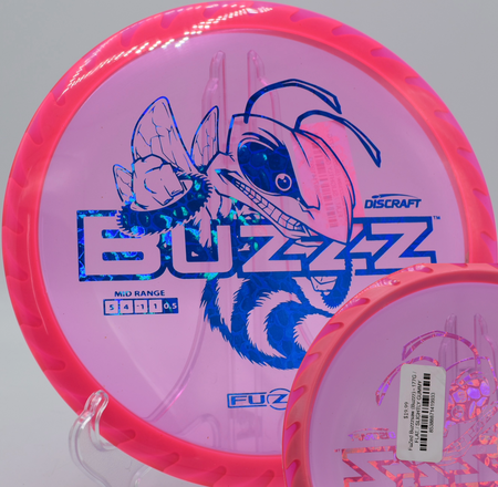 Discraft’s Fuzed Buzzzsaw midrange resting near the basket at Blue Ribbon Pines in East Bethel, Minnesota, known for its strong finish and consistent feel.

