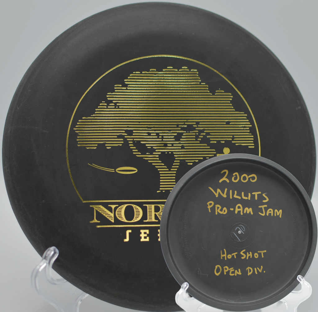 Black 2-Ring San Marino Microbead Aviar w/Pat# (NorCal Series 97–02) resting beside the cage after a clean putt at Mendocino College Disc Golf Course in Ukiah, California.