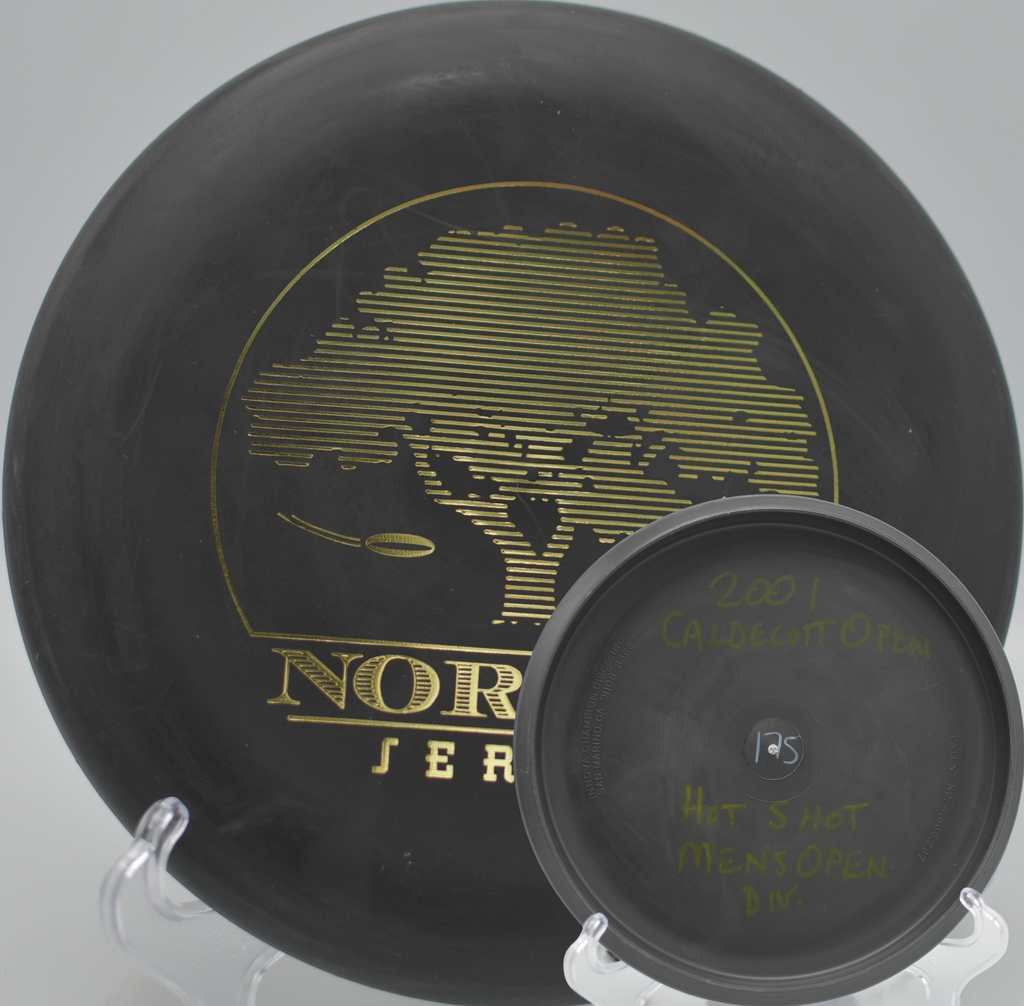 Black 2-Ring San Marino Microbead Aviar w/Pat# (NorCal Series 97–02) resting on the green at Anderson Valley Disc Golf Course in Philo, California.