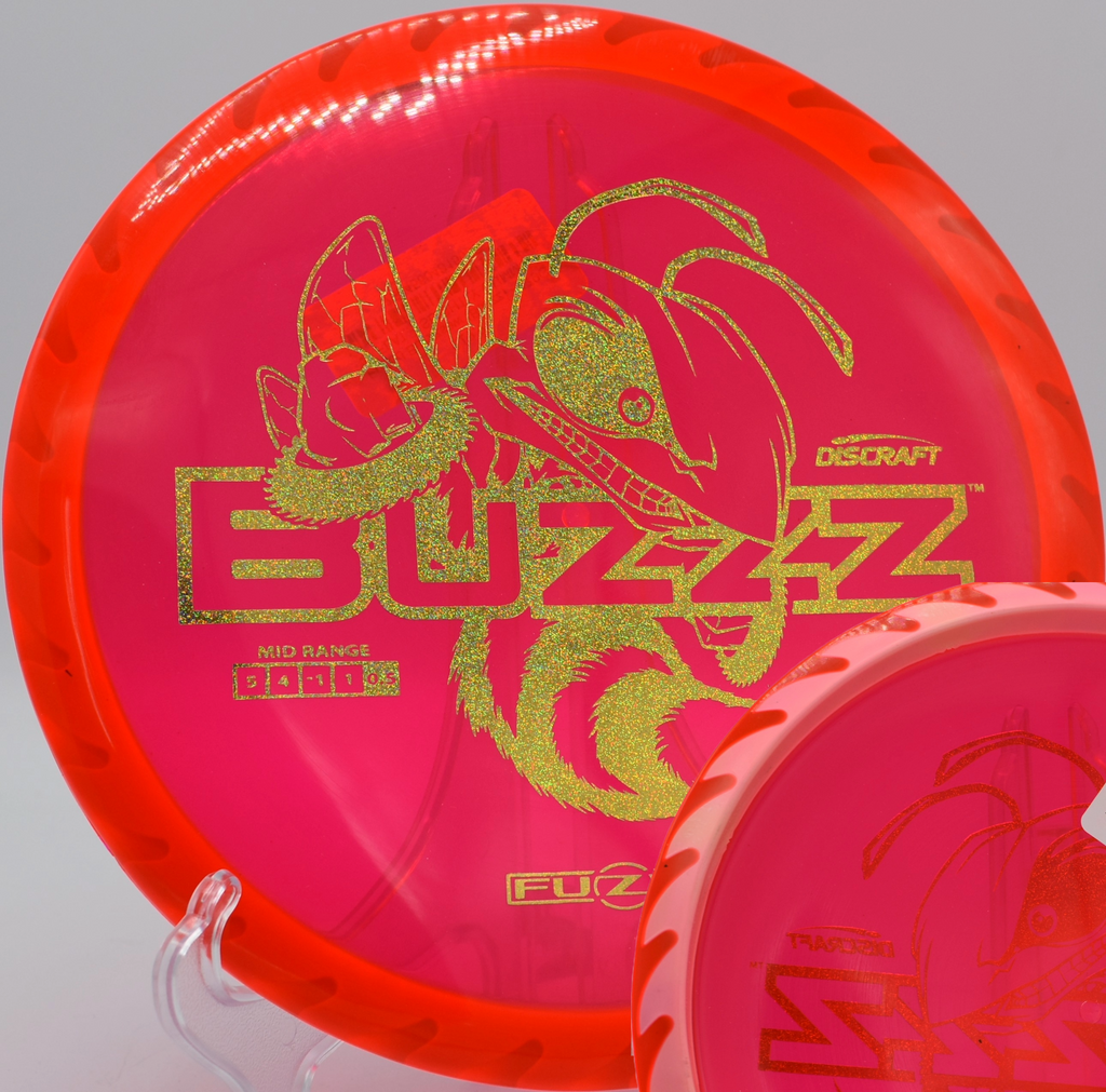 Buzzzsaw midrange by Discraft lying on sun-warmed earth at El Do Disc Golf Course in Long Beach, California, perfect for line shaping and wind-fighting.

